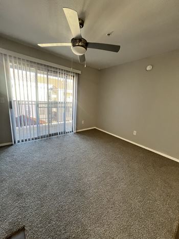 A room with a ceiling fan and carpeted floor.